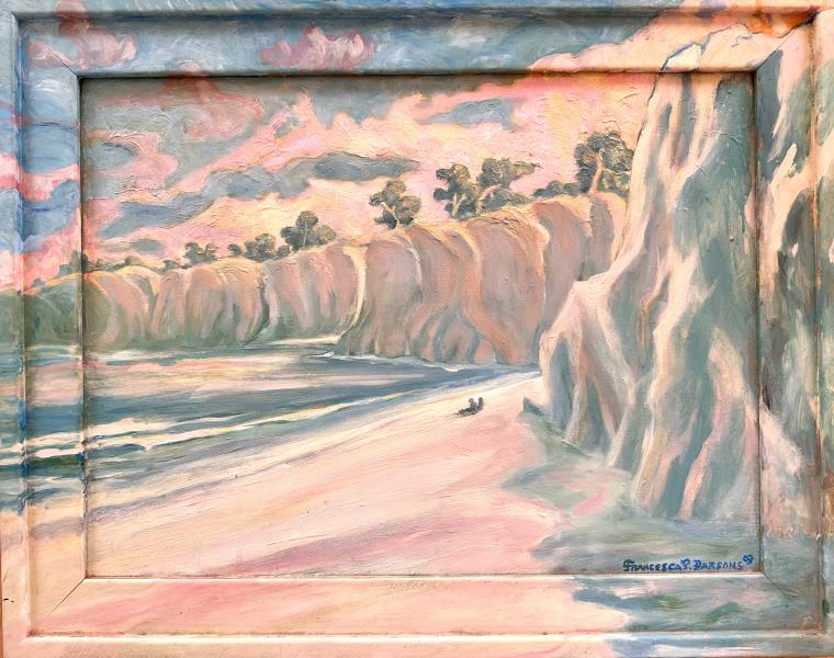 Dark Meets Morning at the Beach by Francesca Perrell is a framed landscape painting of a coastal scene at sunset, rendered in warm golden and green tones. Tall cliffs line the right side and stretch into the distance, topped with small trees. Below, waves roll onto a sandy beach where two small figures sit near the shoreline. The sky is filled with soft, swirling clouds reflecting the warm light.