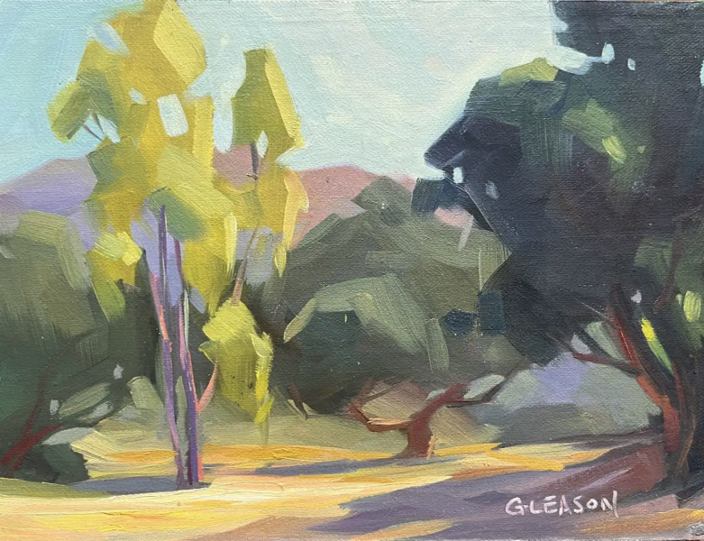 Spring Meadow by Kevin Gleason is a stylized landscape painting featuring bold, angular trees in shades of yellow and deep green. The foreground shows sunlit ground in warm golden tones with long shadows, while soft pink hills and a pale blue sky create depth in the background. The artist’s signature “Gleason” appears in the lower right corner.