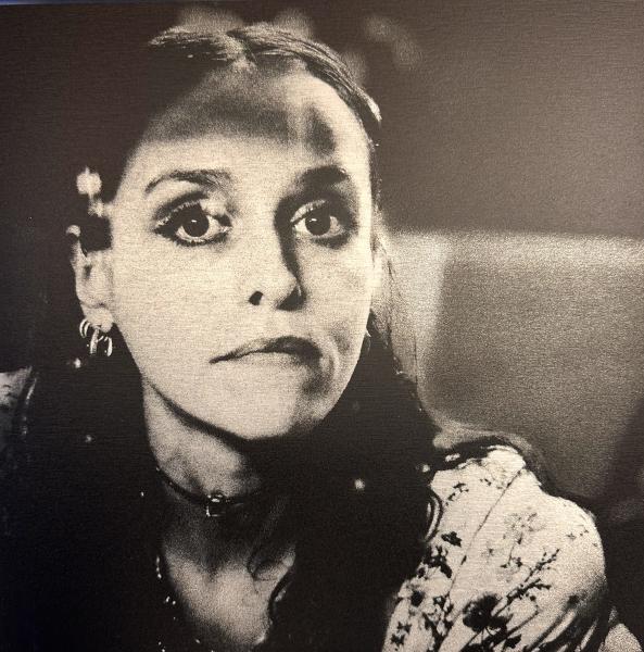 Tess Parks by Dari Mos Black-and-white portrait of a woman with large expressive eyes, wearing hoop earrings and a choker necklace, gazing directly at the camera in soft, moody lighting.