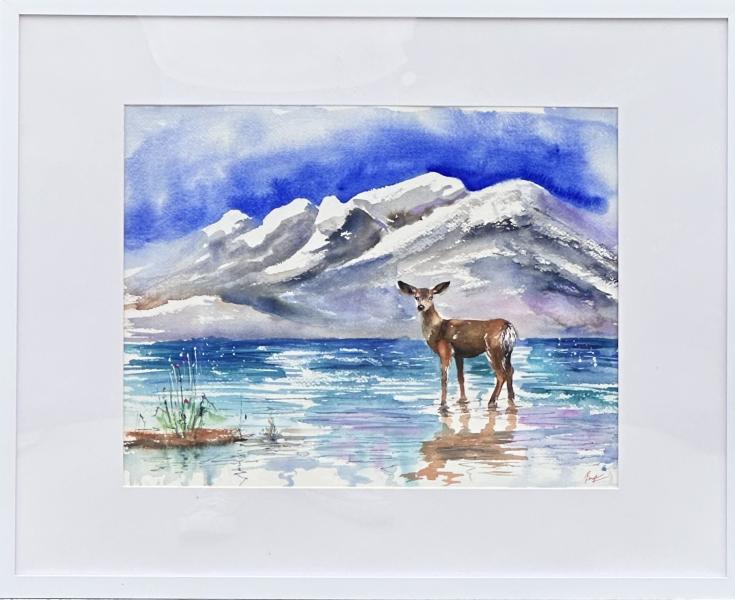 Watercolor painting of a deer standing in shallow water before snow-covered mountains under a deep blue sky.